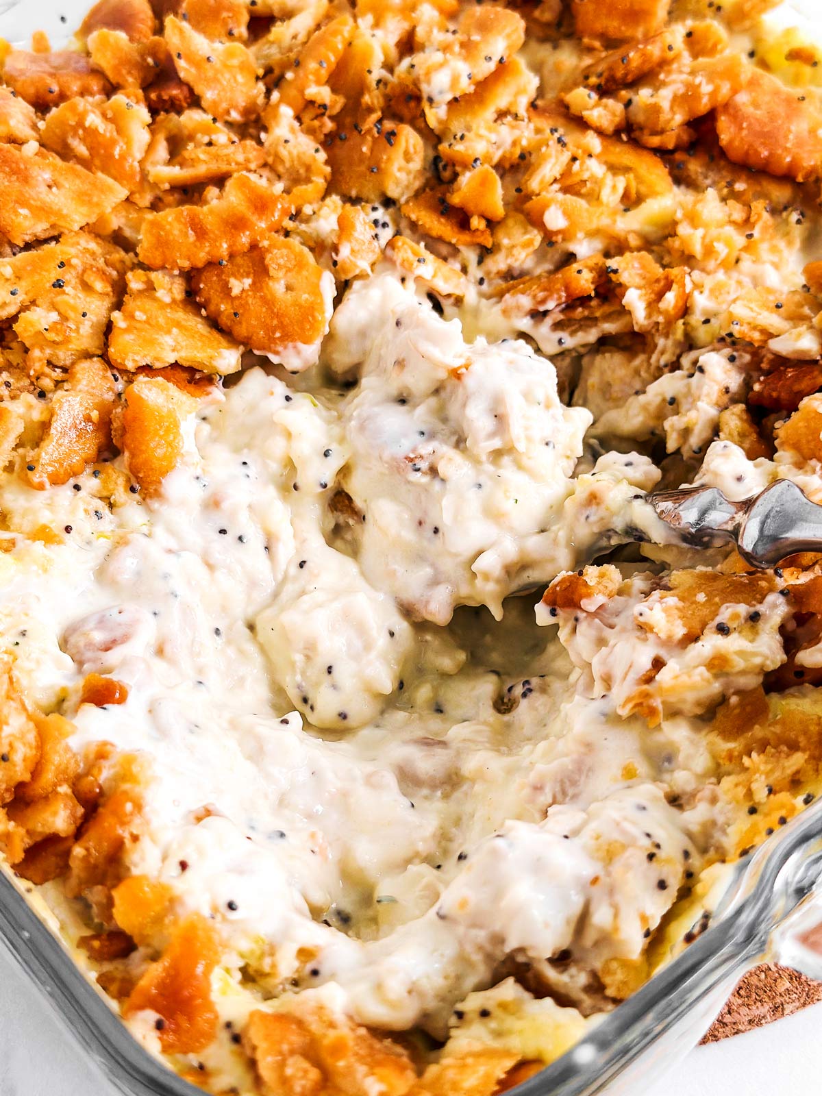 close up view of spoon digging into poppy seed chicken casserole