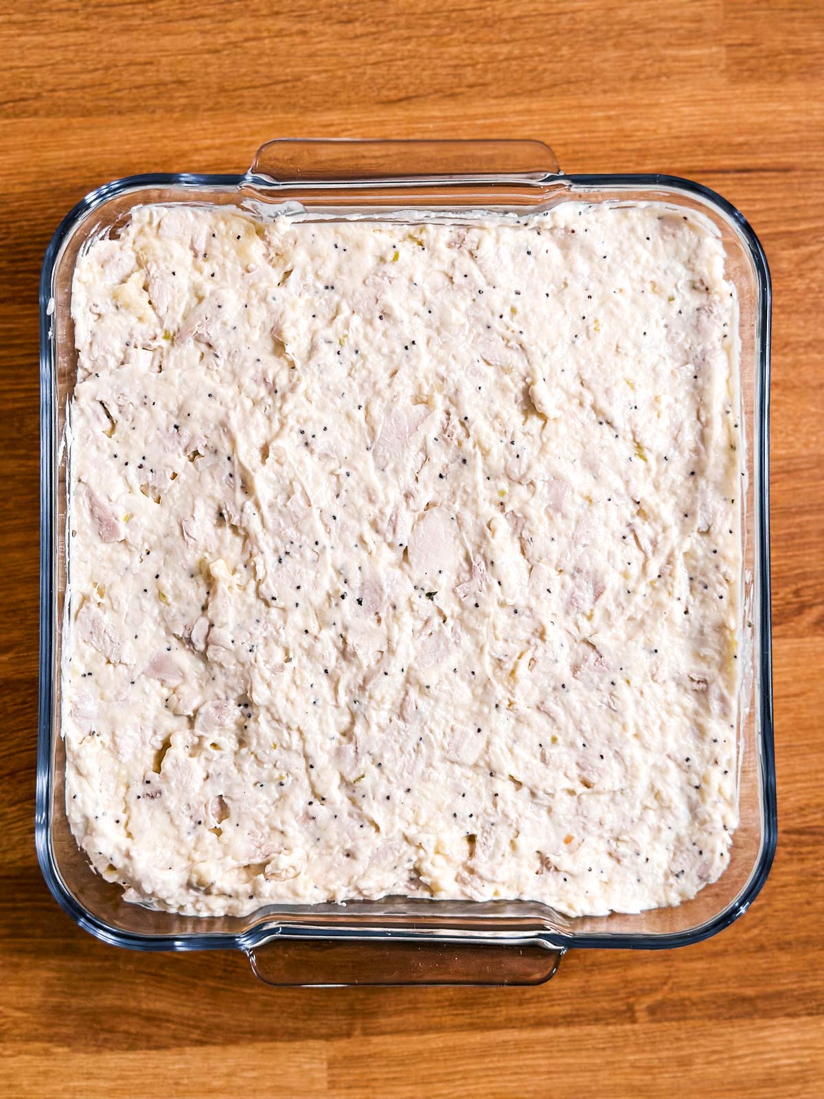 overhead view of poppy seed chicken casserole filling in square glass dish