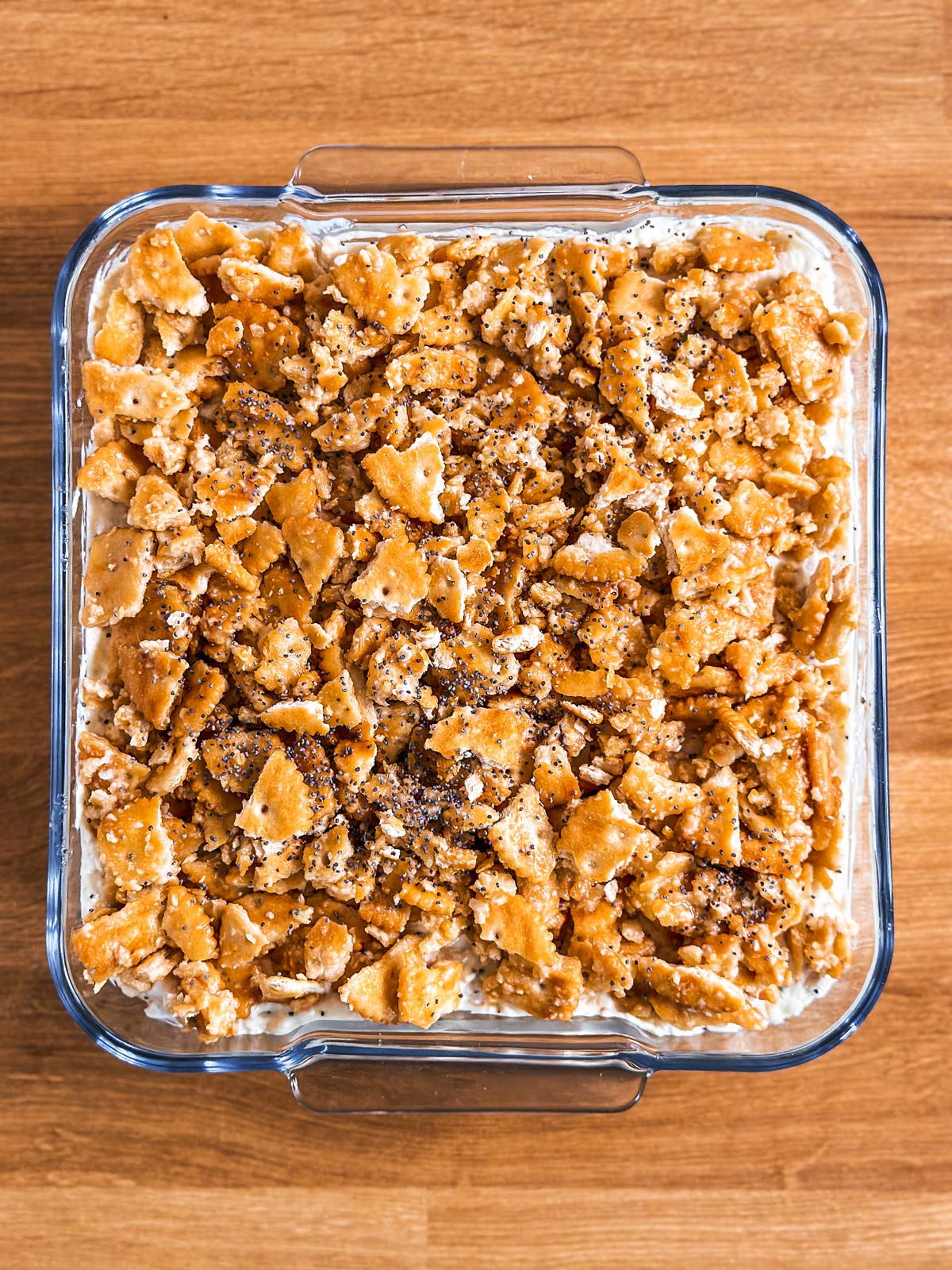 overhead view of unbaked poppy seed chicken casserole in square glass dish