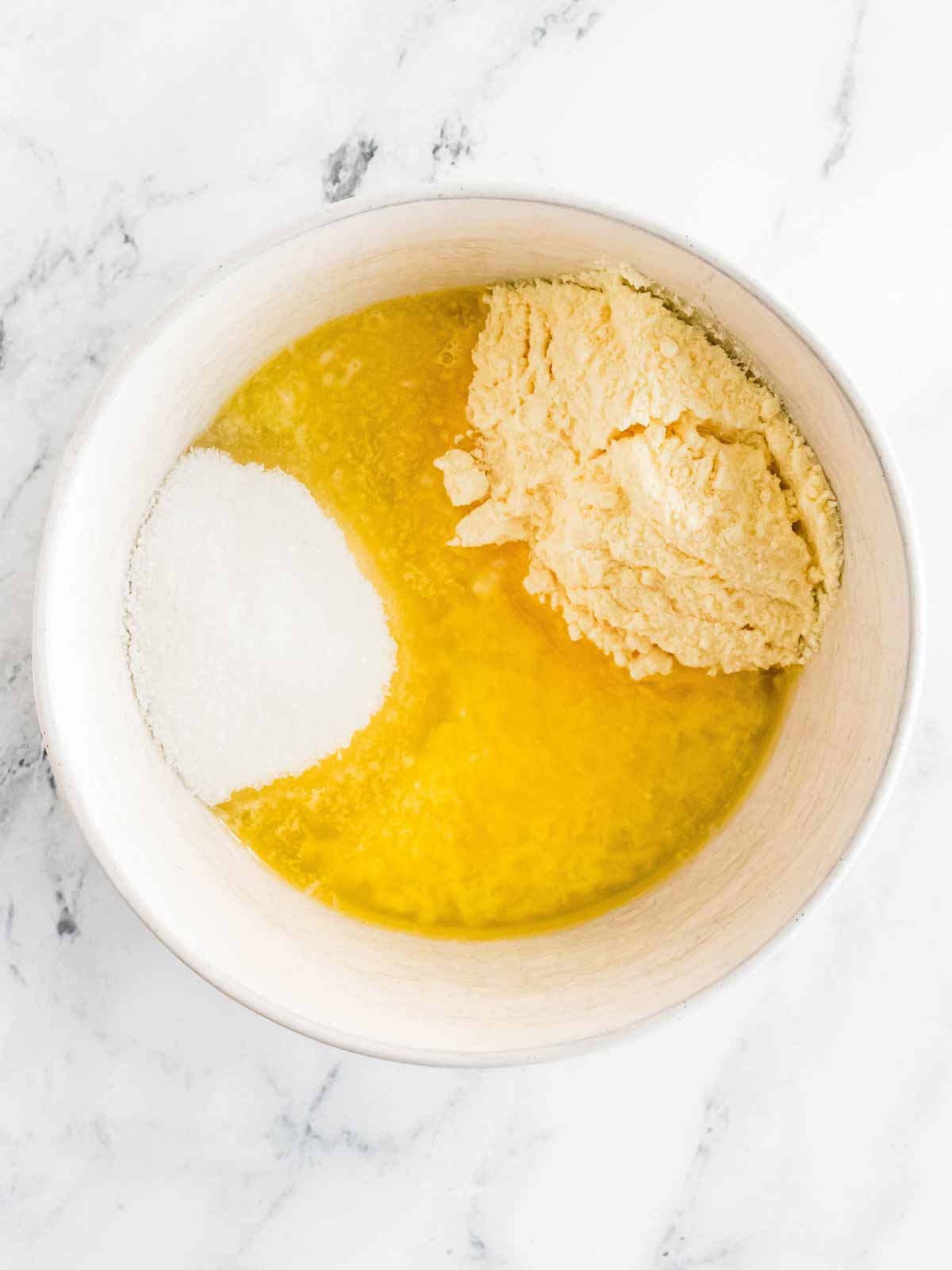 overhead view of vanilla pudding, sugar and milk in small white bowl