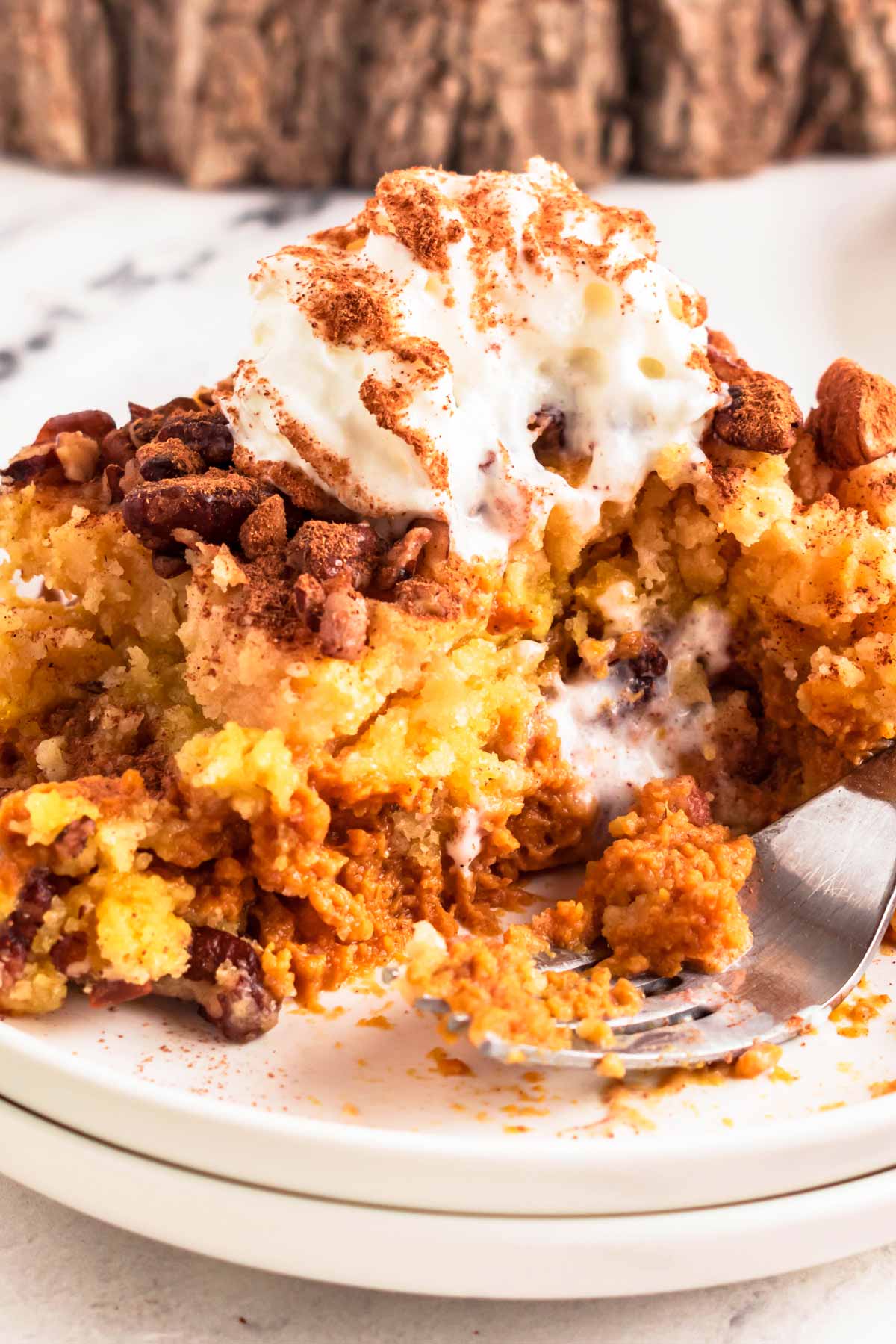 close up view of pumpkin dump cake on plate with a bite taken out