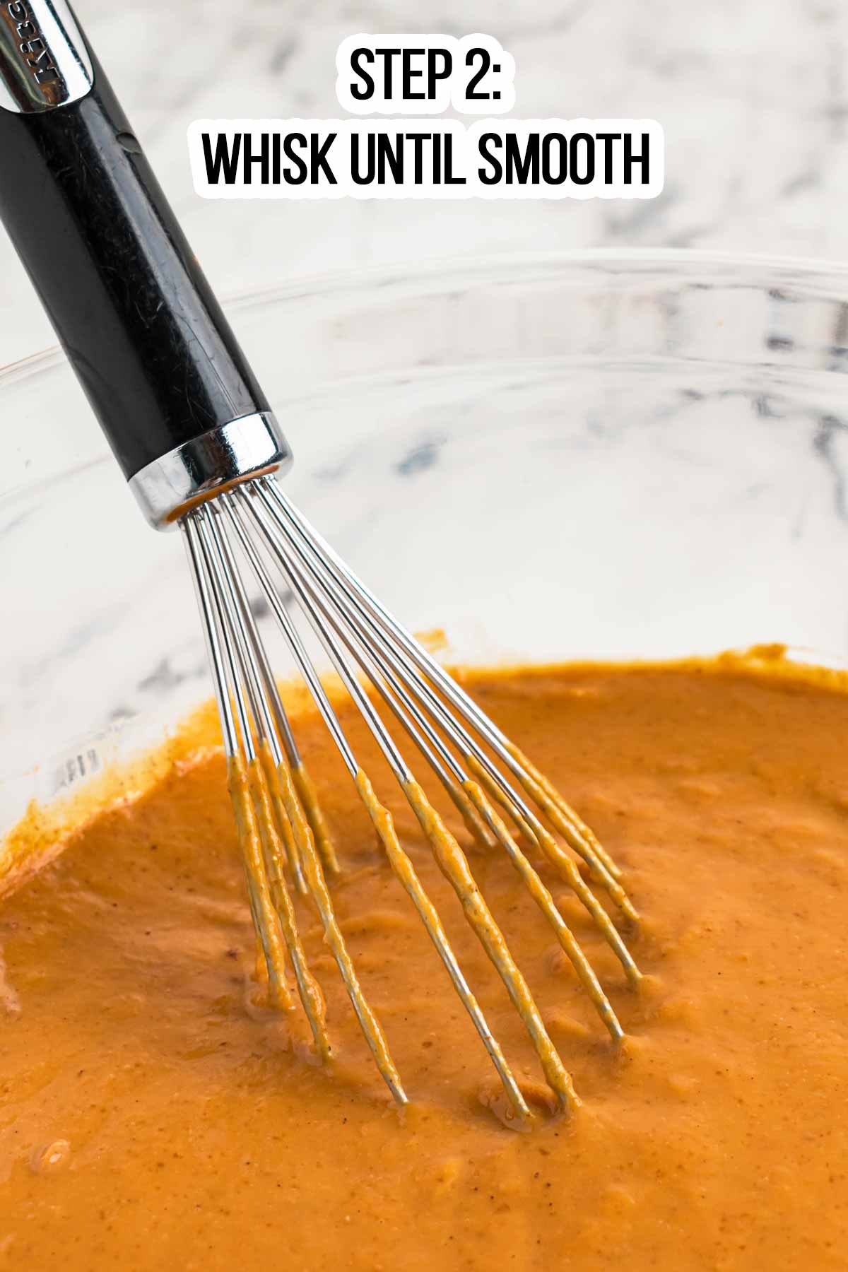 close up view of whisk in bowl with pumpkin dump cake filling